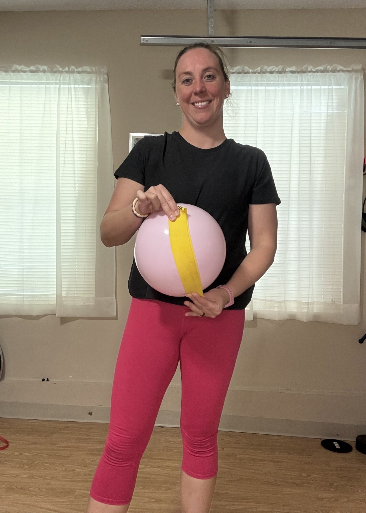 Jen of Moms Fit Life Holding a Ball and Band demonstarting a diastasis recti and the linea alba