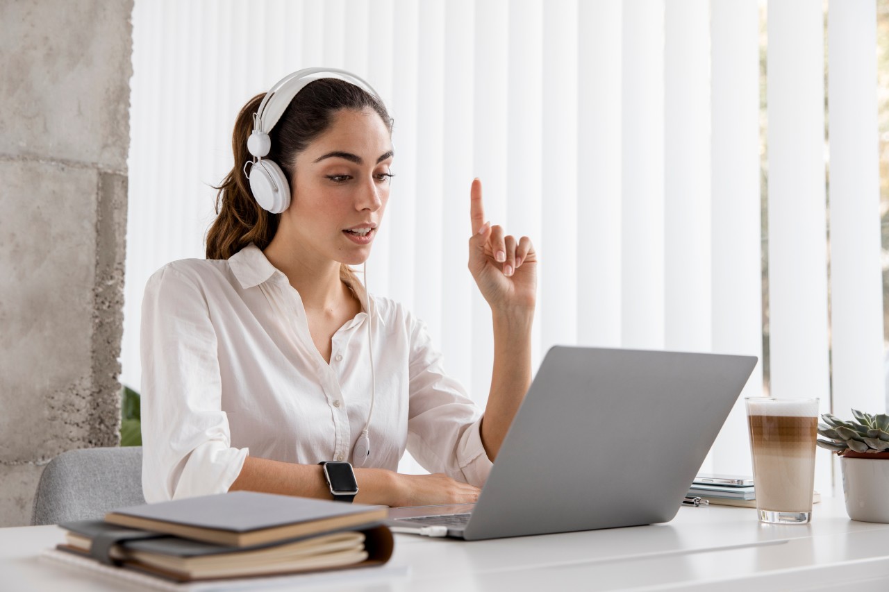 woman at laptop with hand up